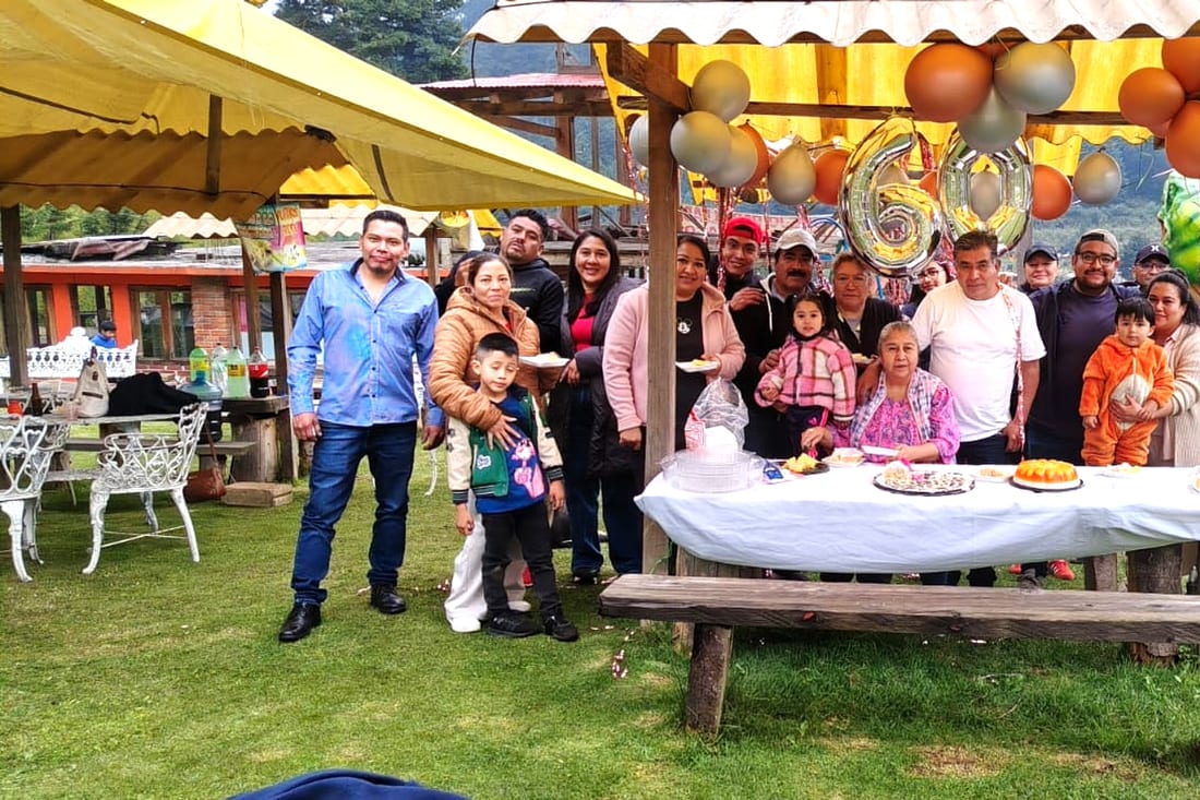Familia celebrando en una palapa decorada con globos dorados y pastel
