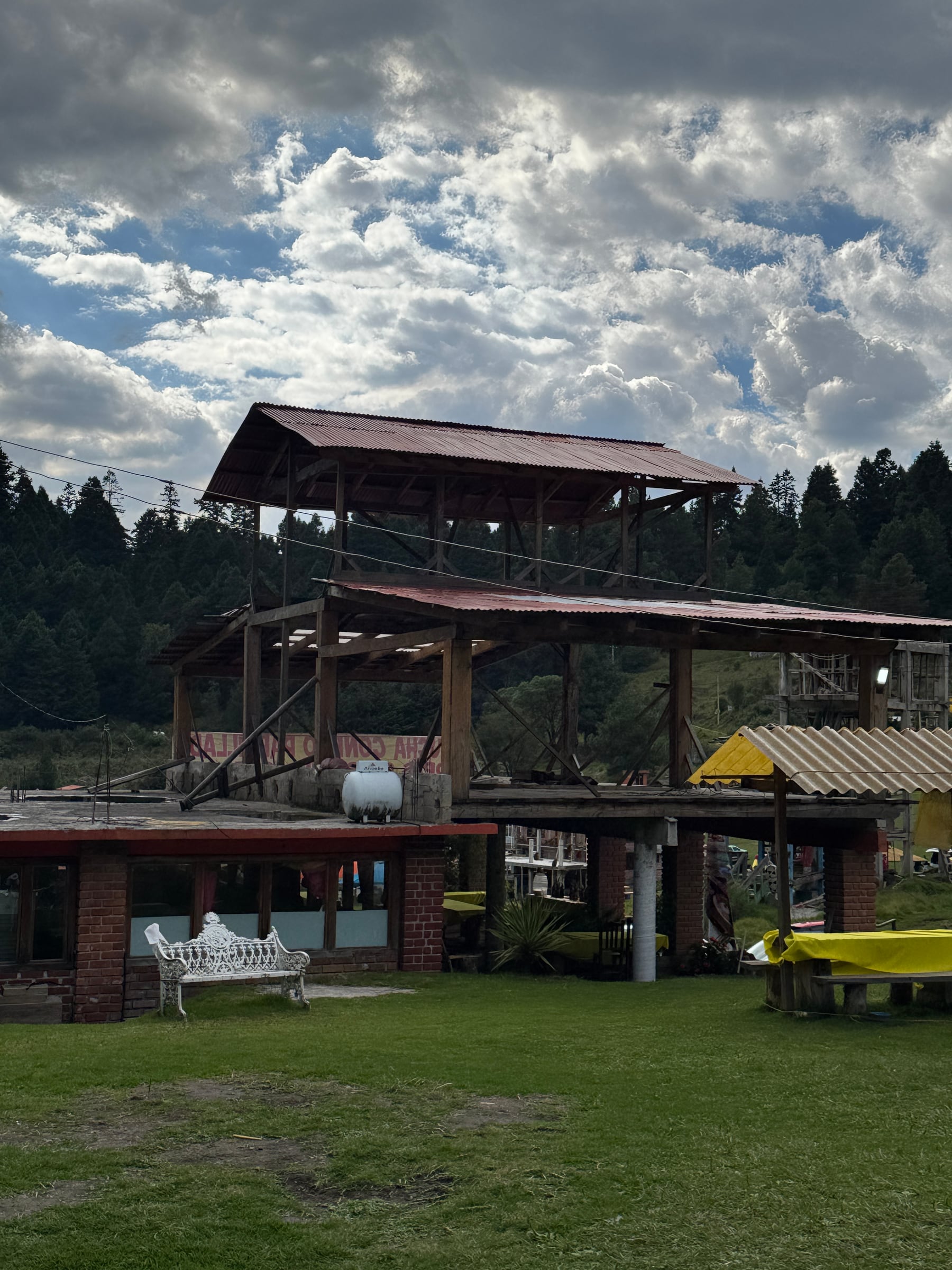 Vista frontal de la hacienda con su estructura de madera y el pinar detrás